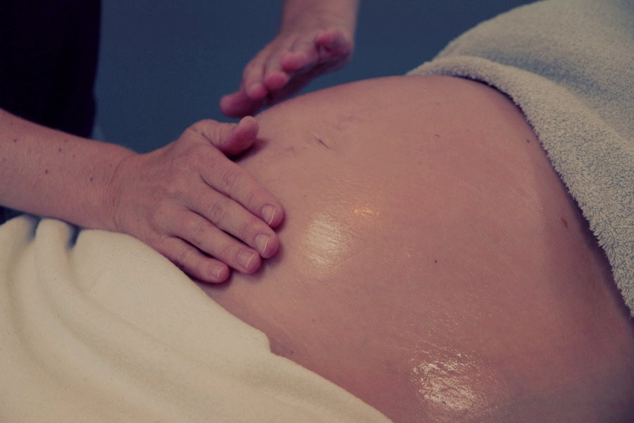 Een zwangerschapsmassage met het insmeren van de buik van de zwangere vrouw